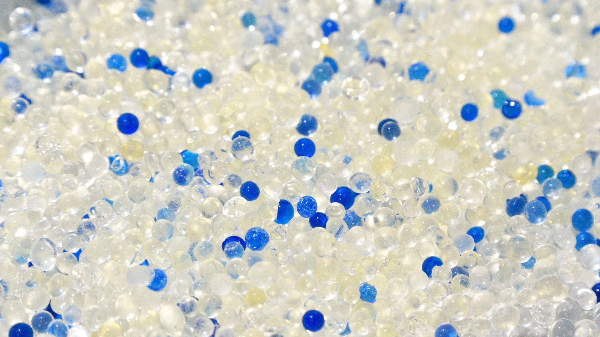 Close-up of polypropylene pellets with an injection molding machine in the background.