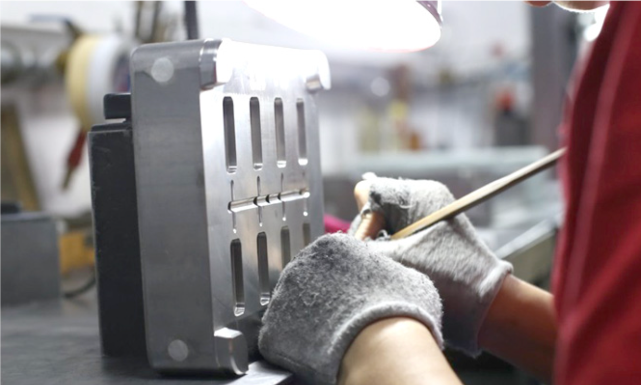 Mold production worker carefully polishing a mold with precision tools.