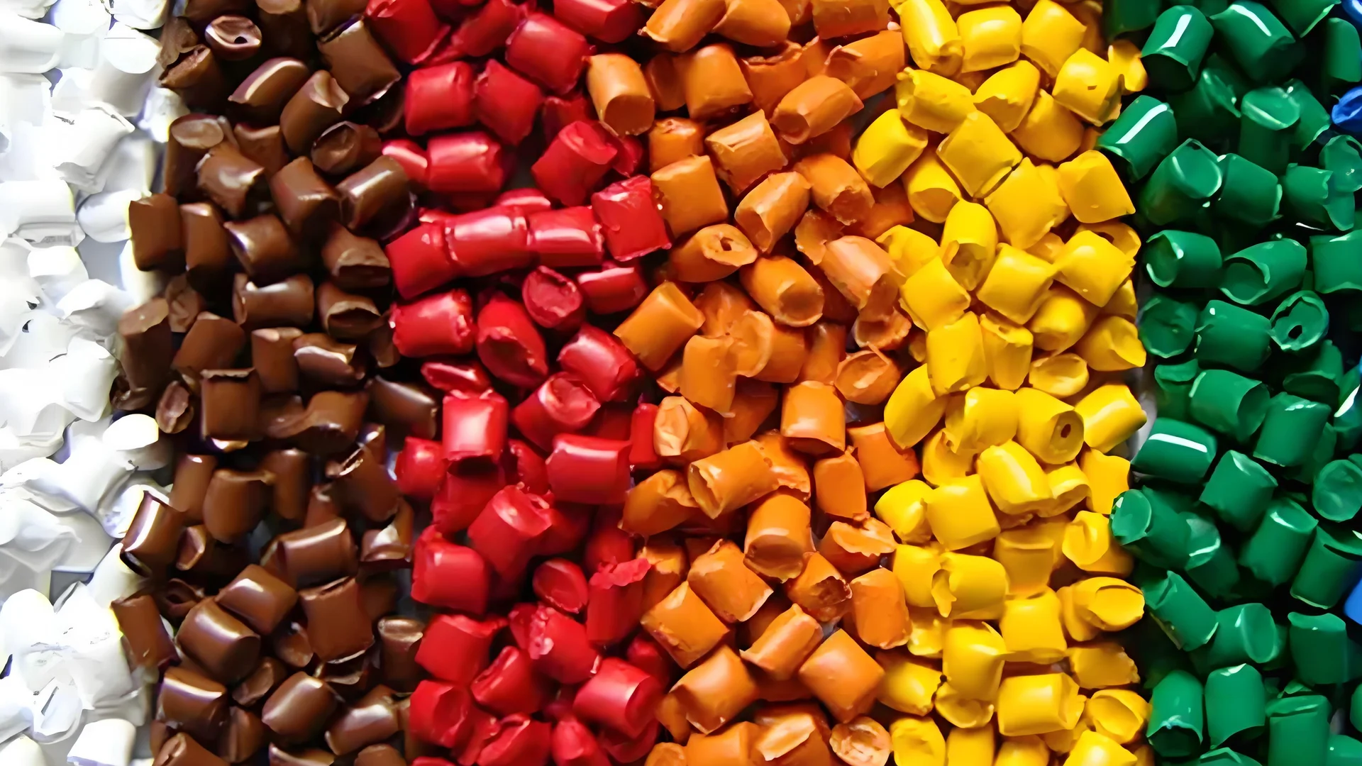 Close-up of colorful plastic pellets used for injection molding on a dark background.